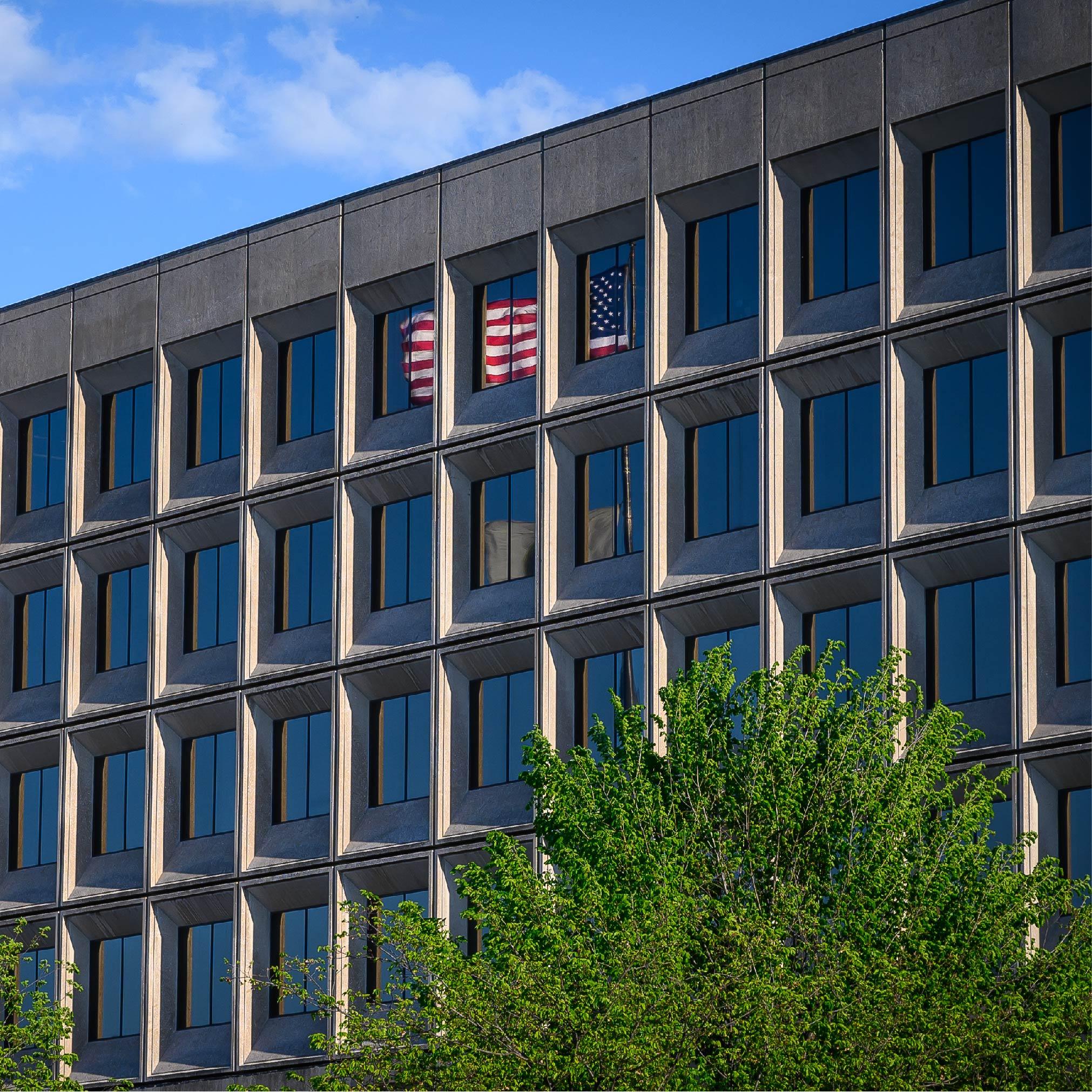 Government building with reflection of American flag showing in windows