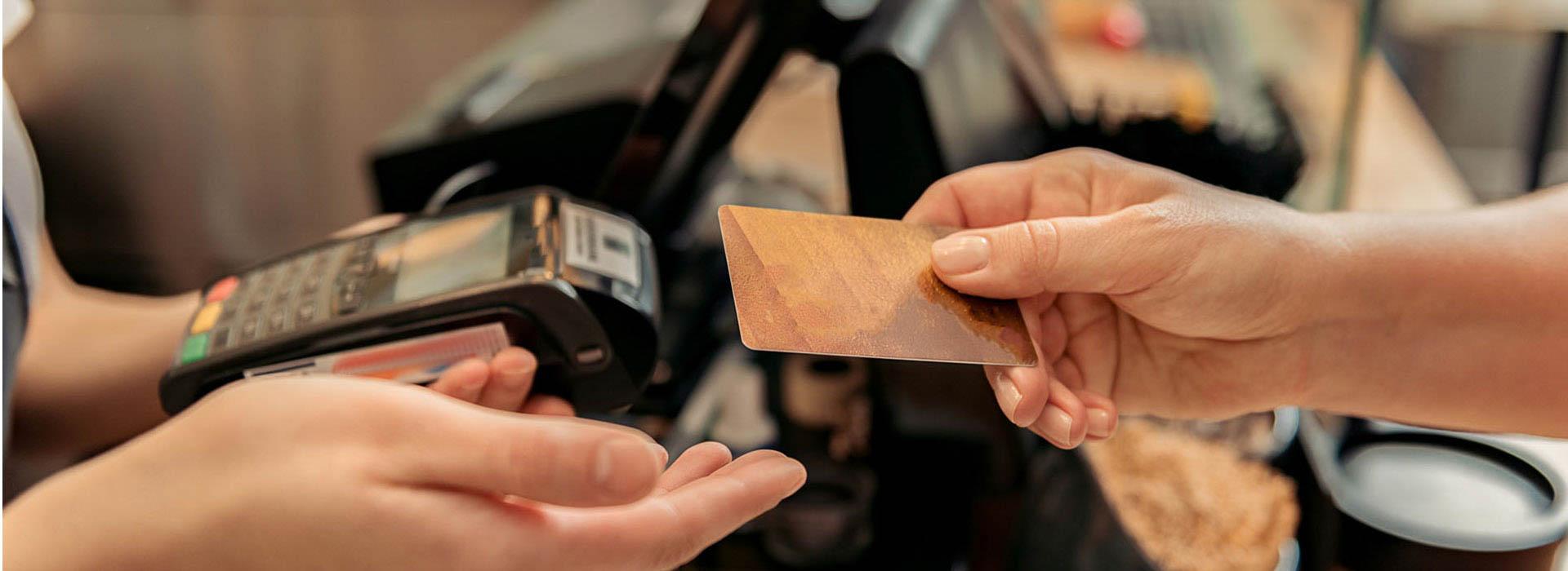 Hand holding credit card over credit card processor